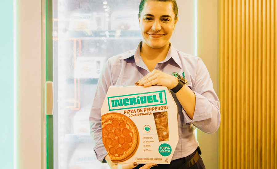 Woman holding frozen pizza with plant-based ingredients